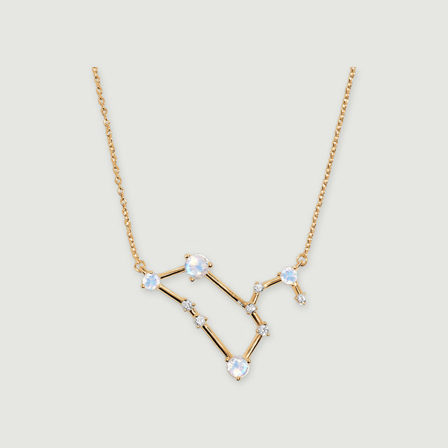 A yellow gold necklace with four pale moonstones and small clear stones rests on a light gray background.