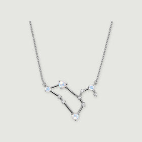 A silver chain frames a geometric pendant with round moonstones and clear accents against light gray.