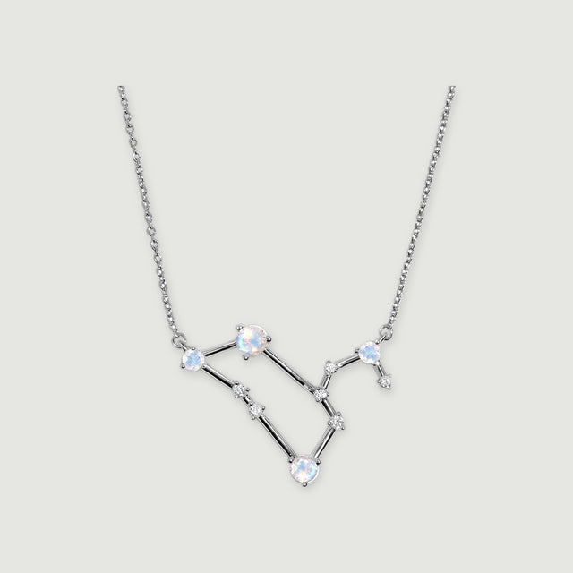A silver chain frames a geometric pendant with round moonstones and clear accents against light gray.