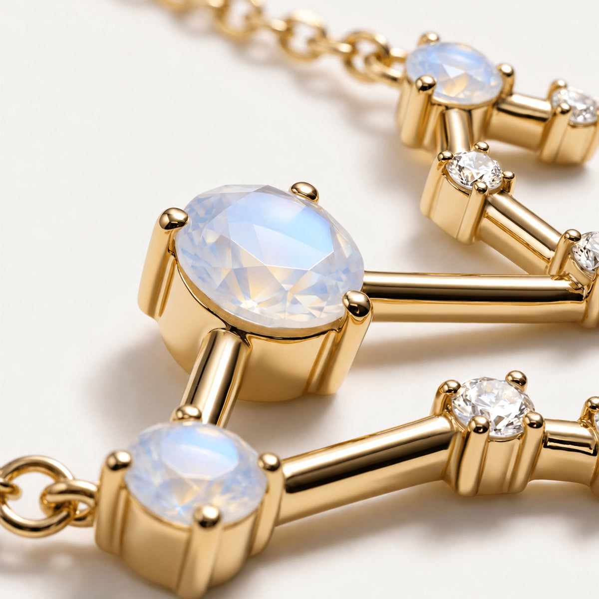 A close view shows a faceted moonstone in yellow gold prongs beside polished bars and clear stones.