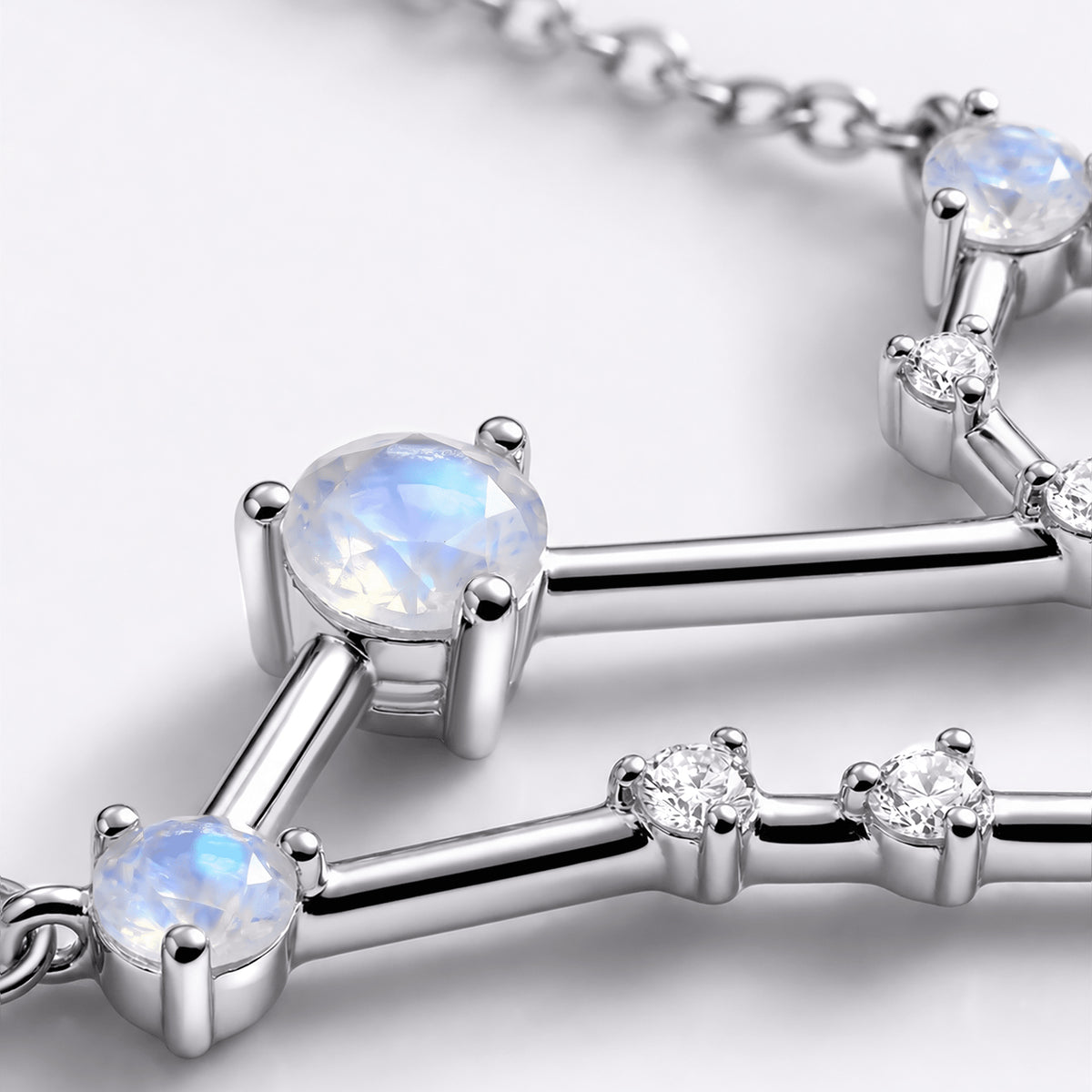 Pale blue reflections appear in round moonstones beside silver prongs and small clear stones.
