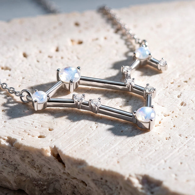 An angled close view reveals raised silver settings and geometric connecting bars above a stone surface.
