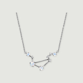 A silver necklace with four round moonstones and small clear stones rests on a light gray background.