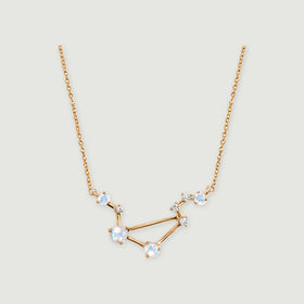 A yellow gold necklace forms an angular constellation with pale blue moonstones on a light gray background.