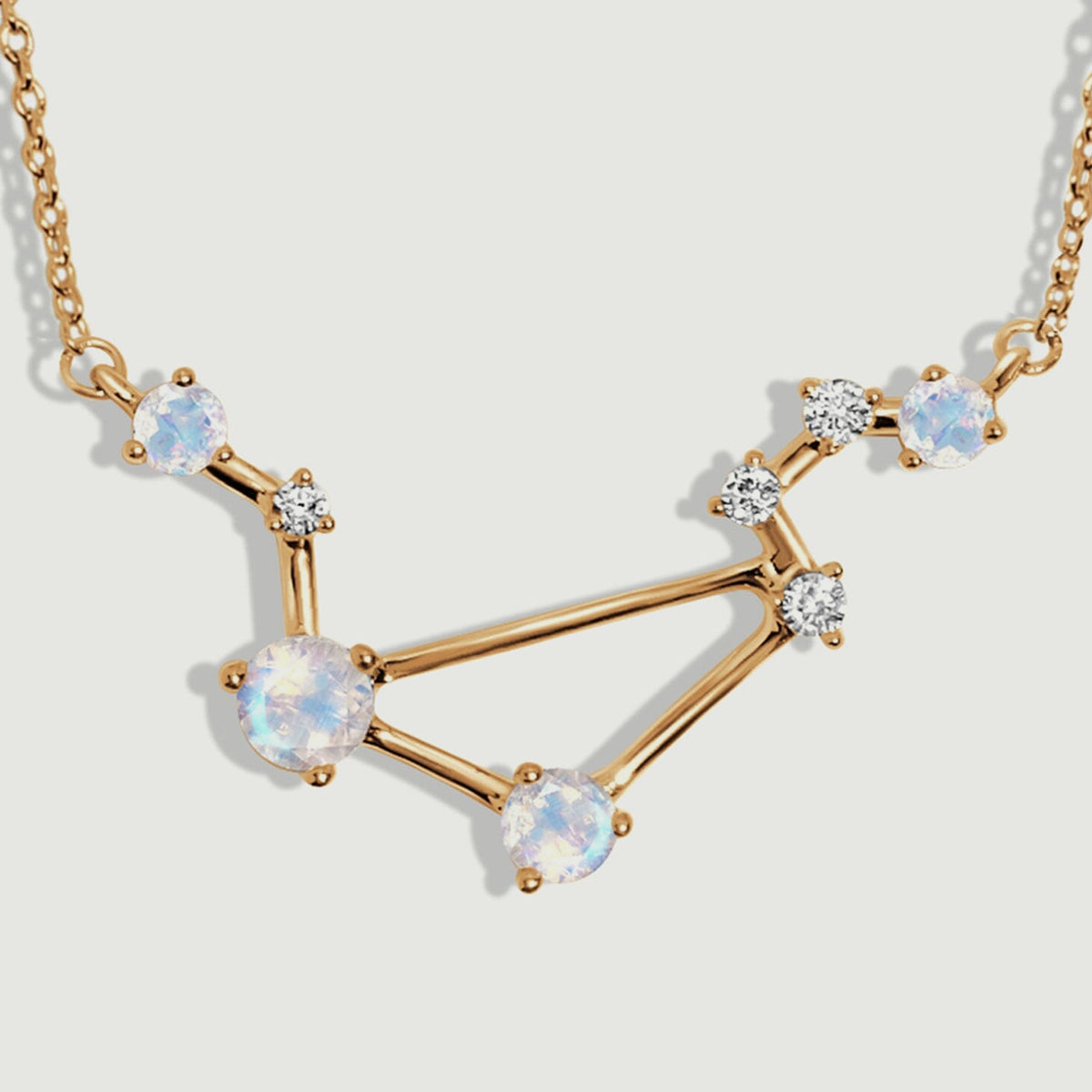 The yellow gold pendant has four iridescent round moonstones connected by slender polished bars.