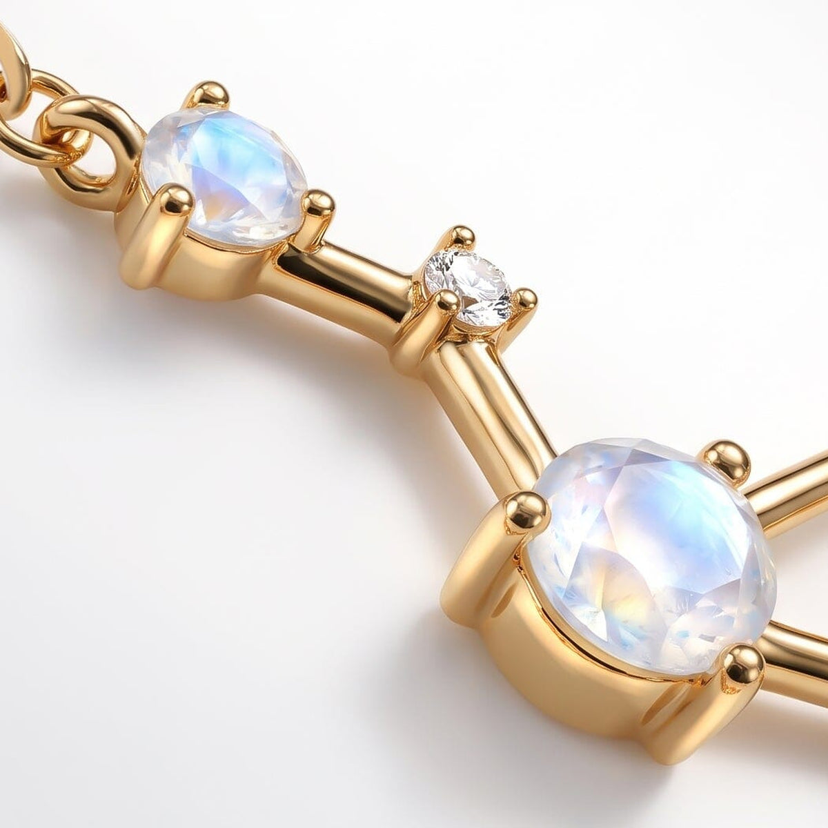 An angled close-up reveals yellow gold prongs around a faceted moonstone and a smaller clear stone.