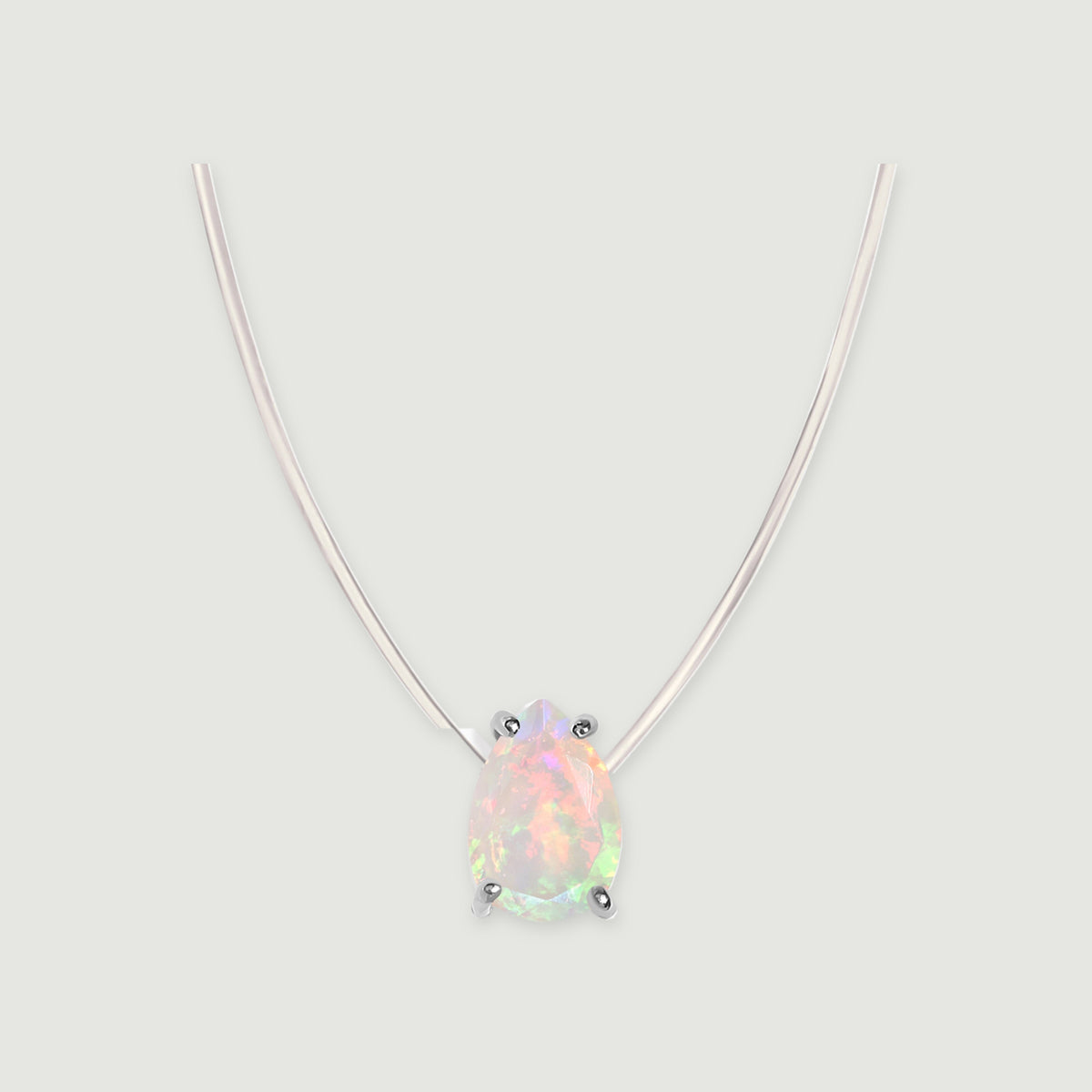 A pear-shaped opal with four silver prongs hangs from a transparent cord against a light gray background.