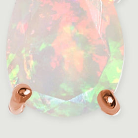 A close-up reveals the lower opal facets and two rounded rose gold prongs on a light gray surface.