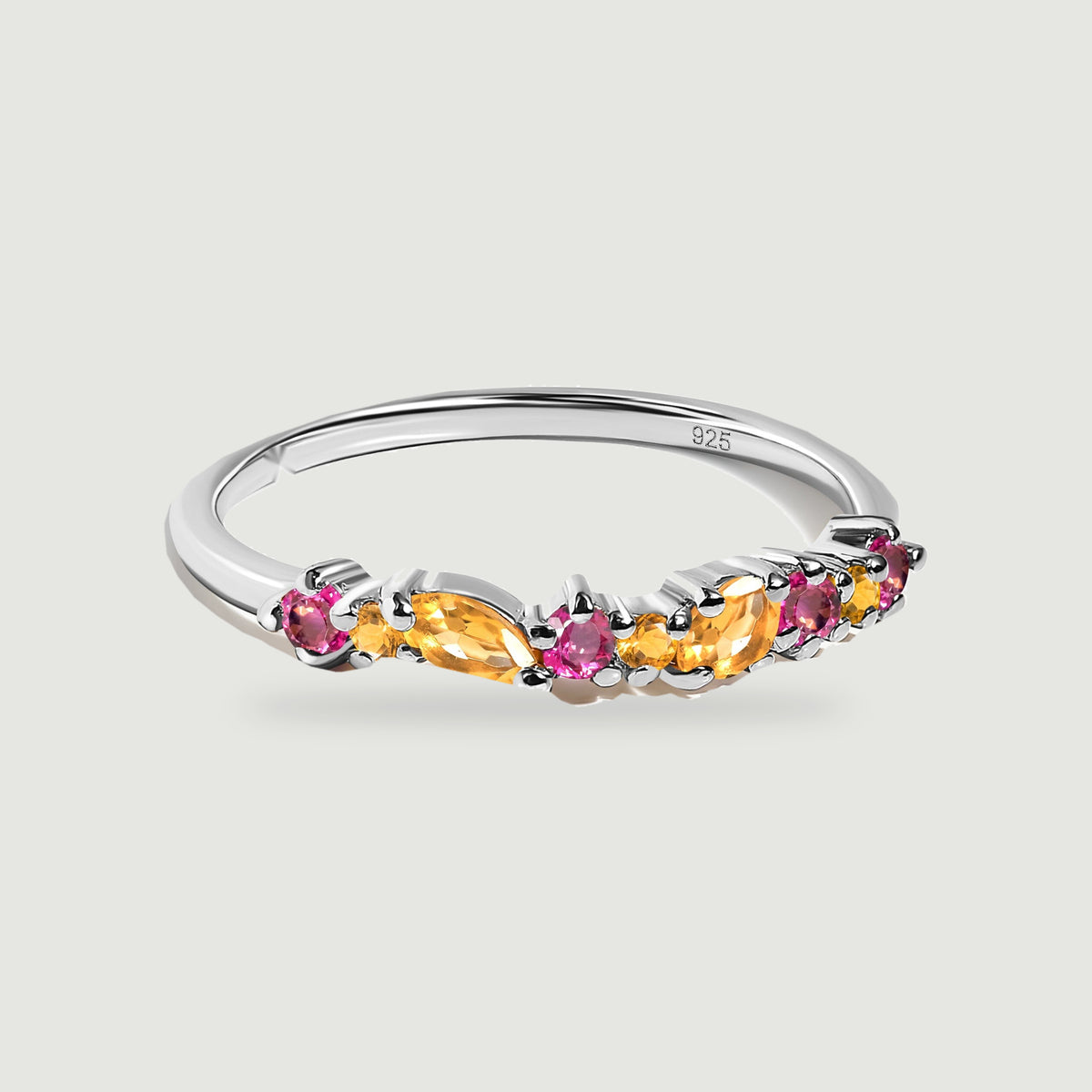 A sterling silver ring with orange citrine and round pink topaz rests on a pale gray background.