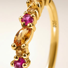 A close view shows gold prongs around faceted orange citrine and bright pink topaz.