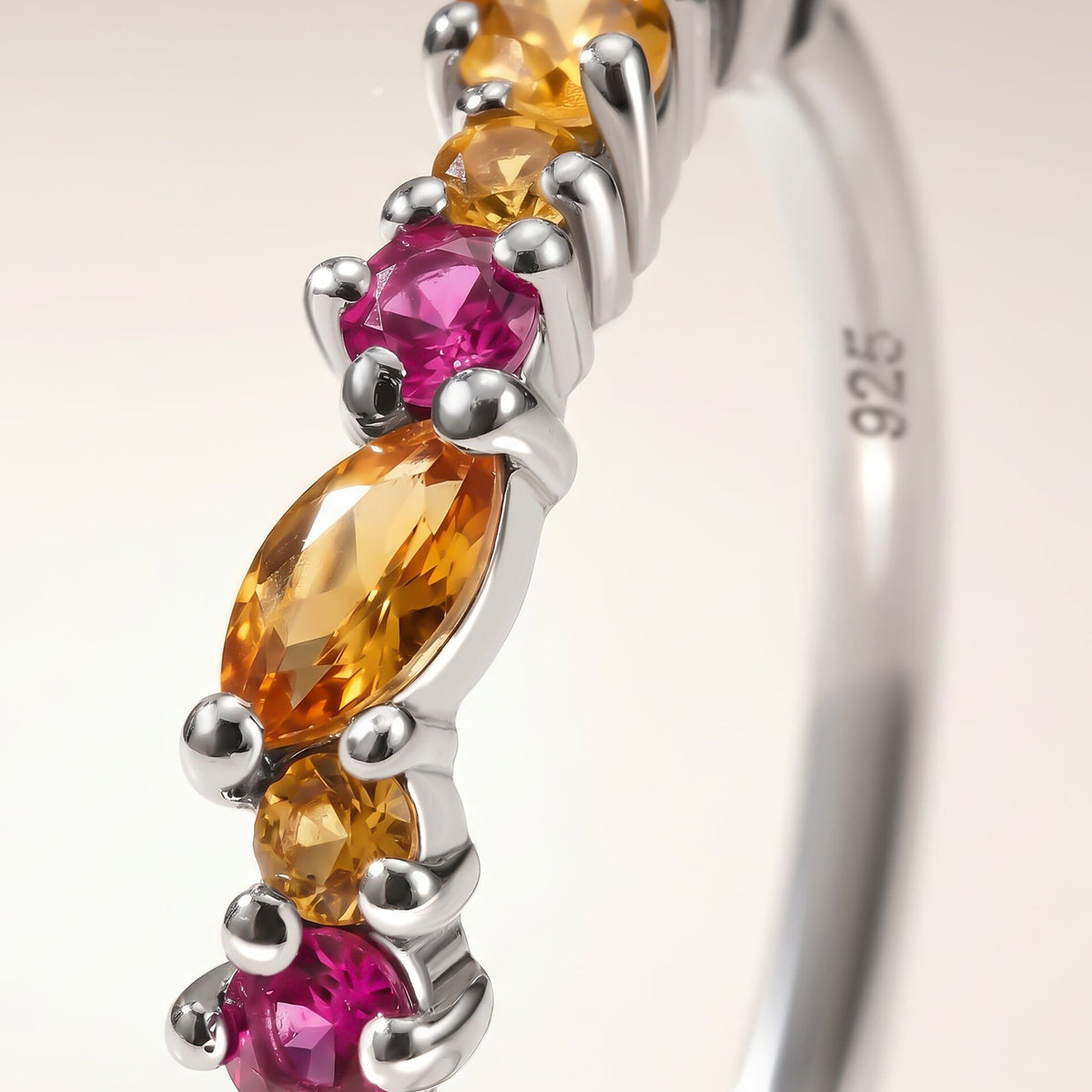 A close view shows silver prongs around faceted orange citrine and bright pink topaz.