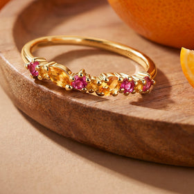 The yellow gold vermeil gemstone ring lies on a wooden tray beside orange fruit.