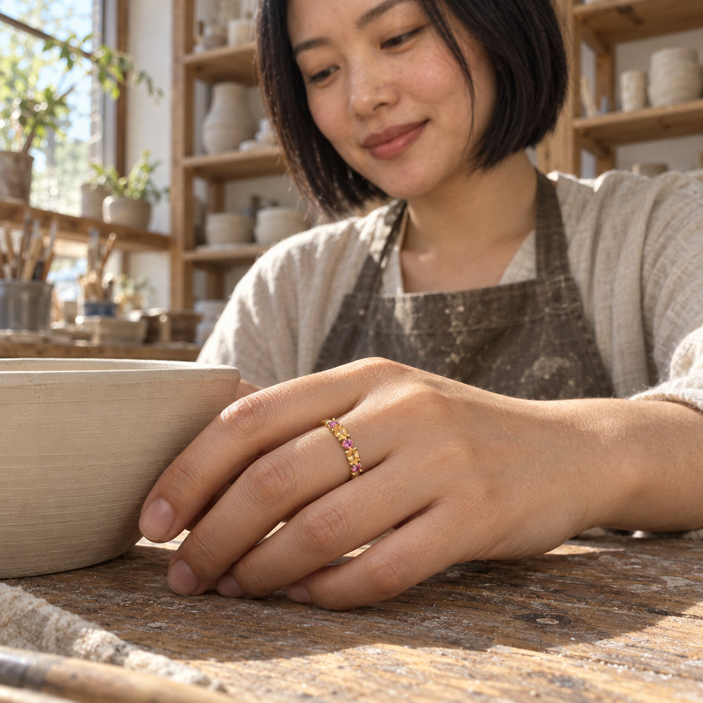 A woman wears the yellow gold vermeil gemstone ring while resting her hand beside a clay bowl in a pottery studio.