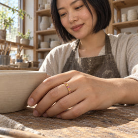 A woman wears the yellow gold vermeil gemstone ring while resting her hand beside a clay bowl in a pottery studio.