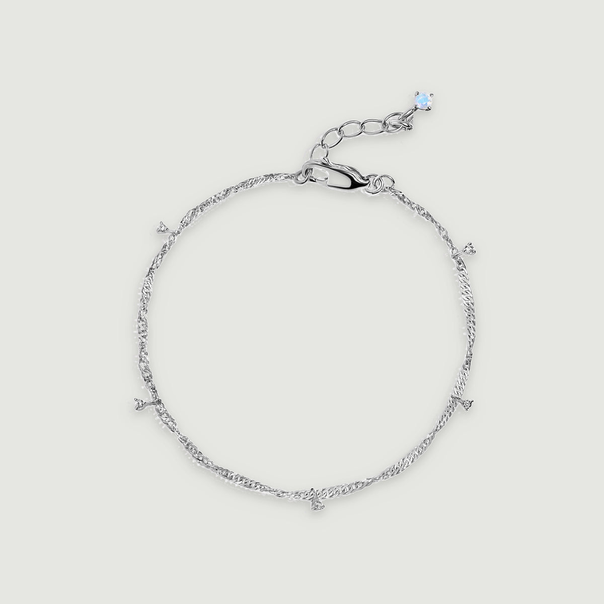 A sterling silver anklet forms an oval with five small clear gemstone drops and an extension chain.