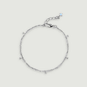 A sterling silver anklet forms an oval with five small clear gemstone drops and an extension chain.