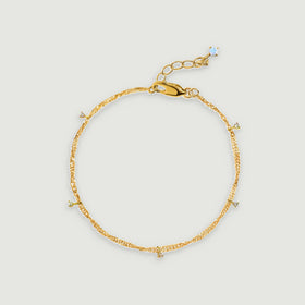A yellow gold vermeil anklet is arranged in an oval with clear gemstone drops and a lobster clasp.