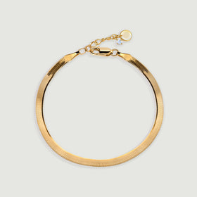 A yellow gold herringbone bracelet rests in a rounded loop with a lobster clasp at the top.