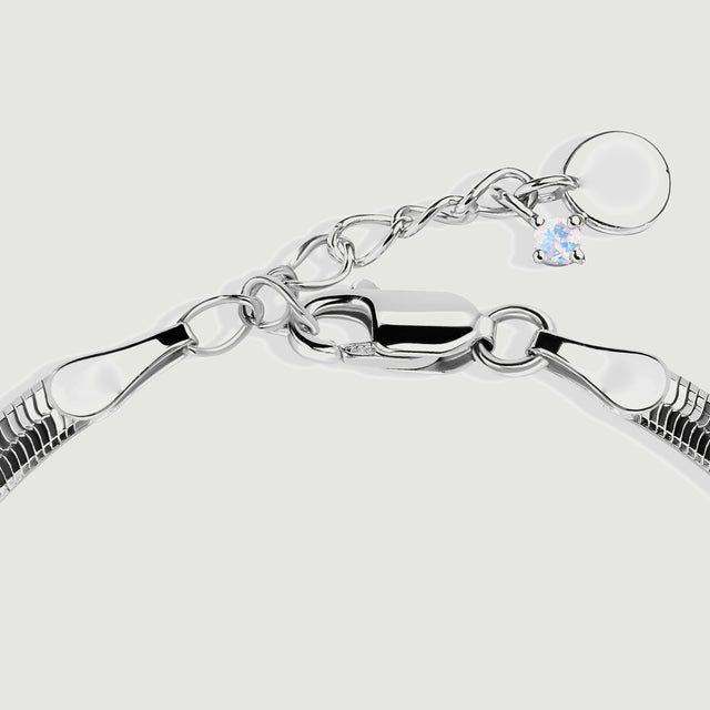 The silver lobster clasp sits beside oval extension links and a small pale stone charm.