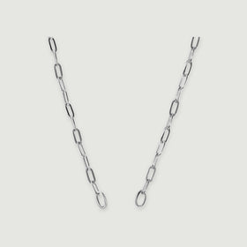 A polished silver chain with elongated links and two round end rings is centered on a pale grey surface.