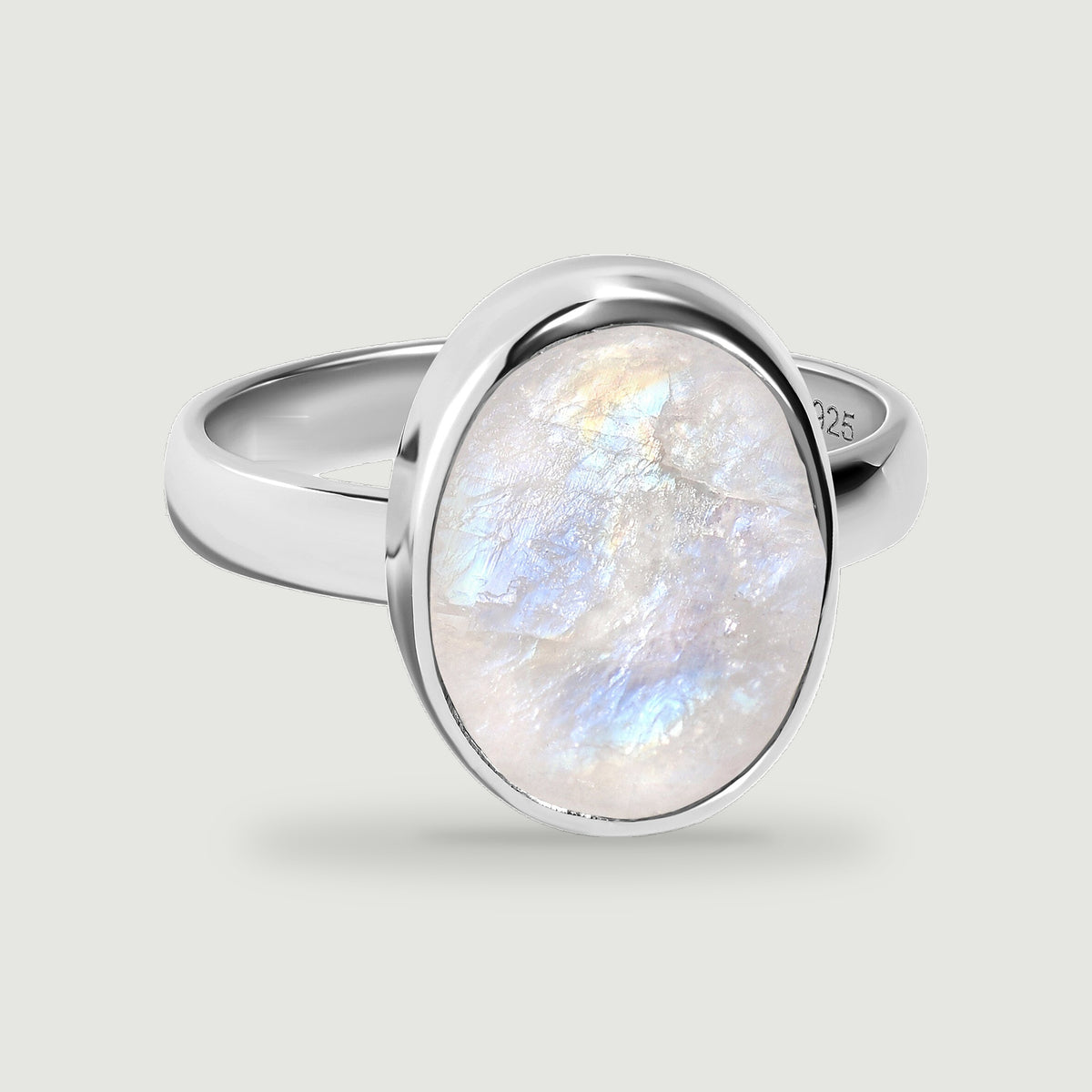 An oval moonstone with blue and peach reflections sits in a polished sterling silver ring.