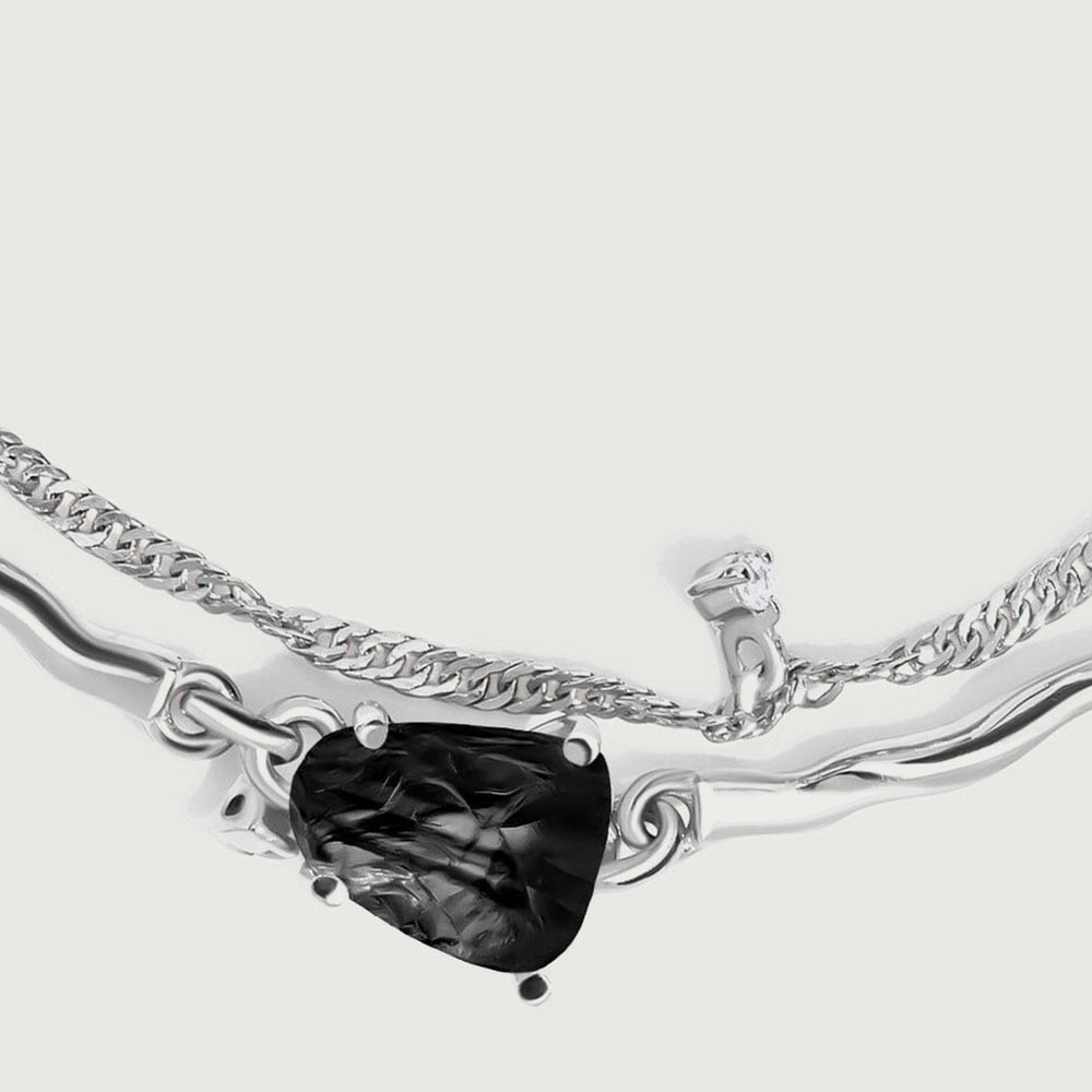 A close view shows the ridged black stone held by silver prongs between two polished curved links.