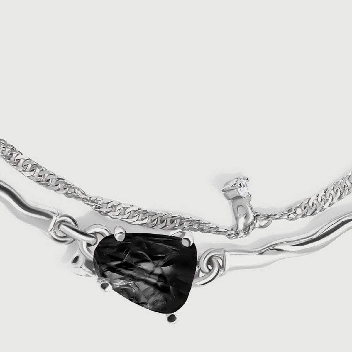 A close view shows the ridged black stone held by silver prongs between two polished curved links.