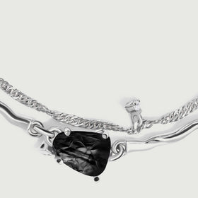 A close view shows the ridged black stone held by silver prongs between two polished curved links.