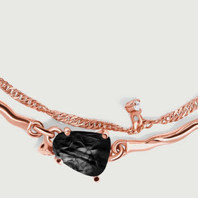 A textured black stone meets warm rose gold links in a close view of the bracelet front.