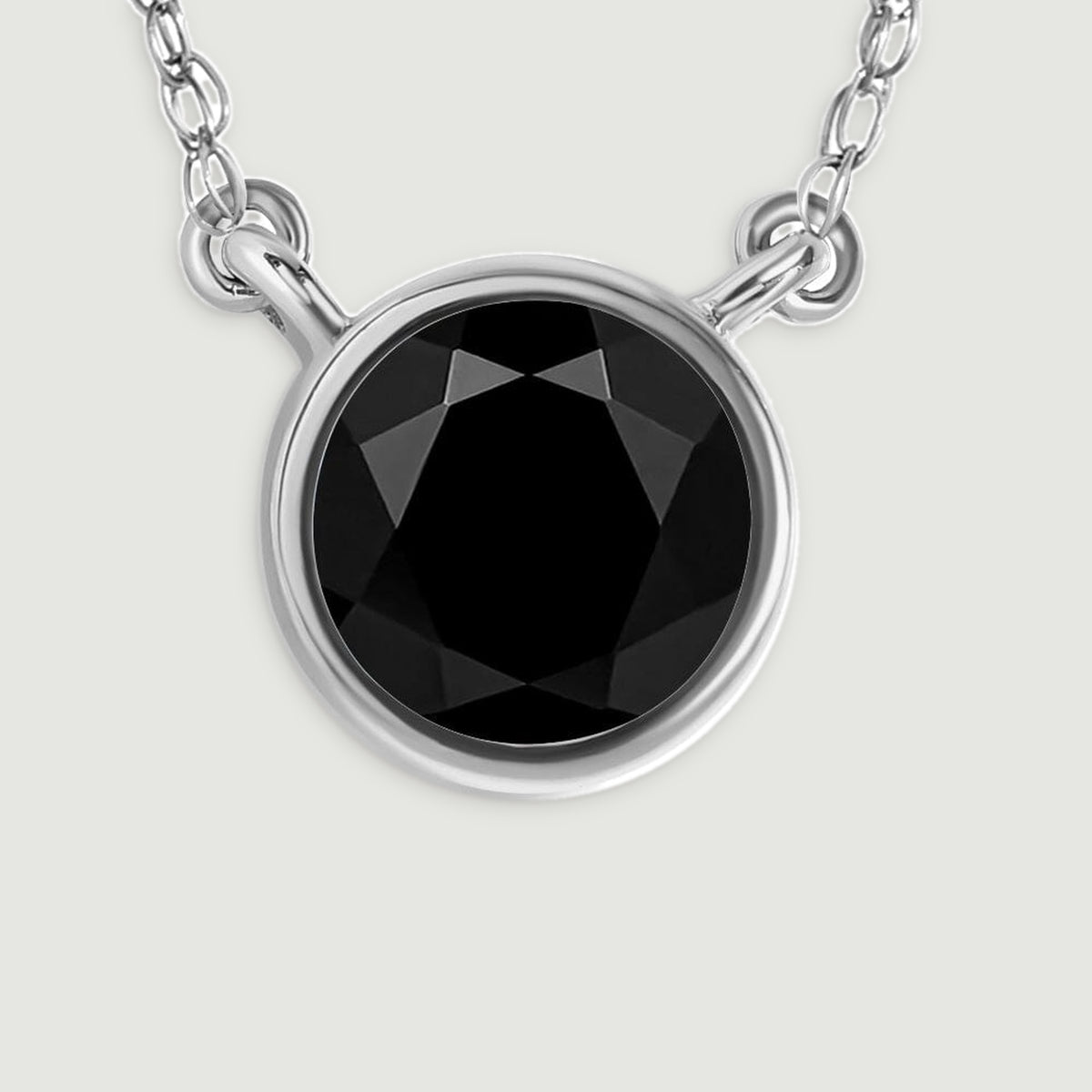 A detailed view reveals the glossy black stone, bright white gold bezel, and paired chain connections.