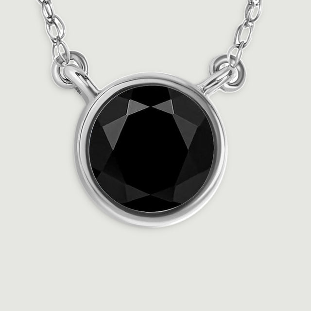 A detailed view reveals the glossy black stone, bright white gold bezel, and paired chain connections.