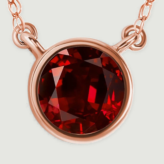 The rose gold pendant fills the frame, showing the round red stone and curved bezel edge.