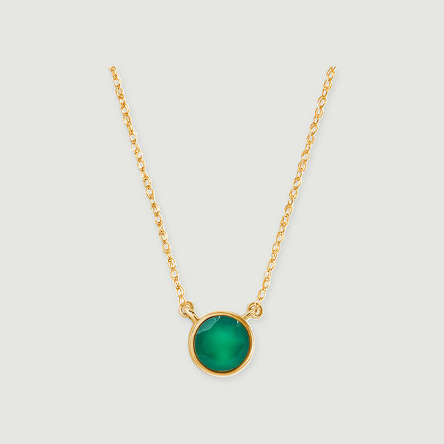 A round green onyx pendant in yellow gold hangs between two fine chain sections on a light gray background.