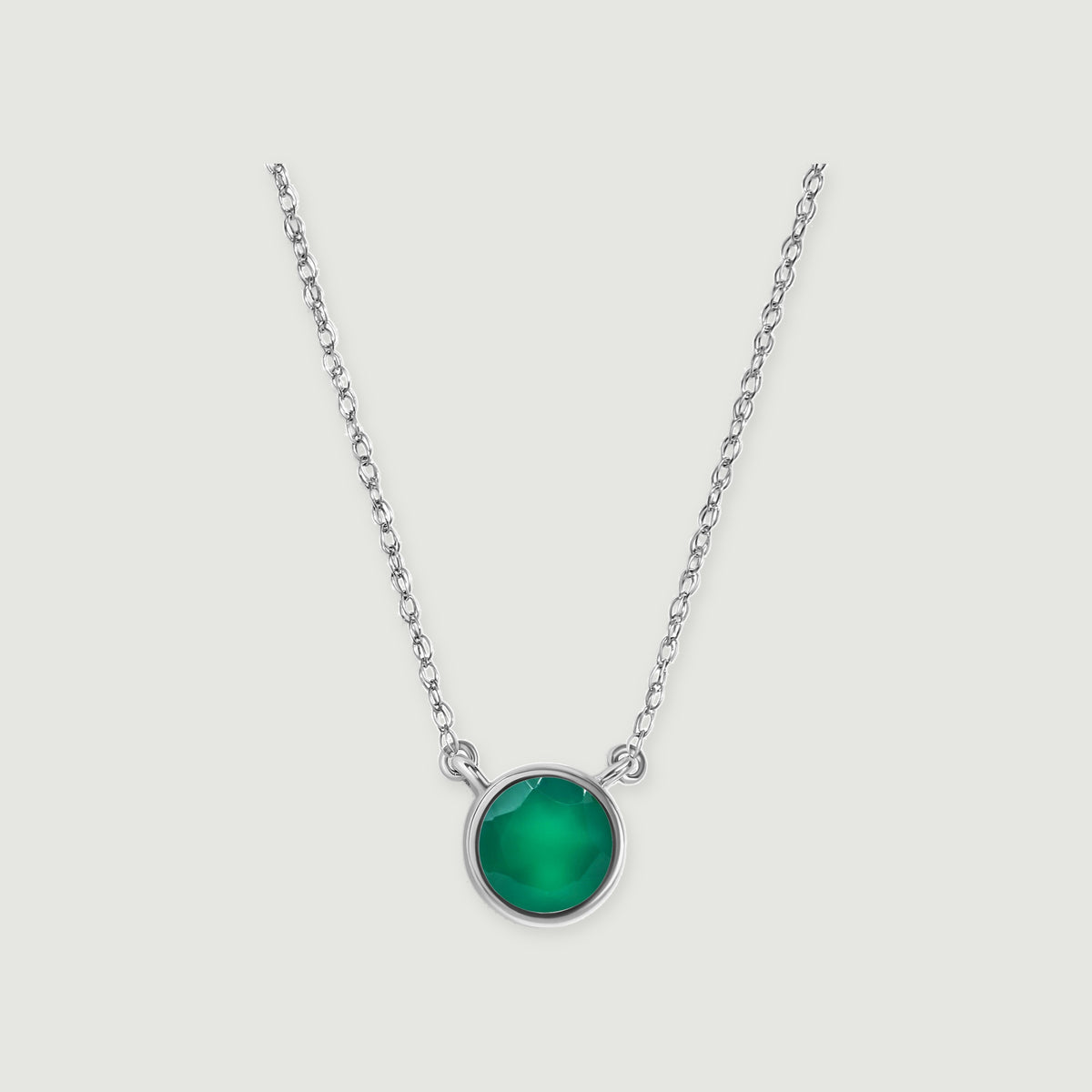 A green onyx stone in a polished white gold setting is attached to a delicate chain on soft gray.