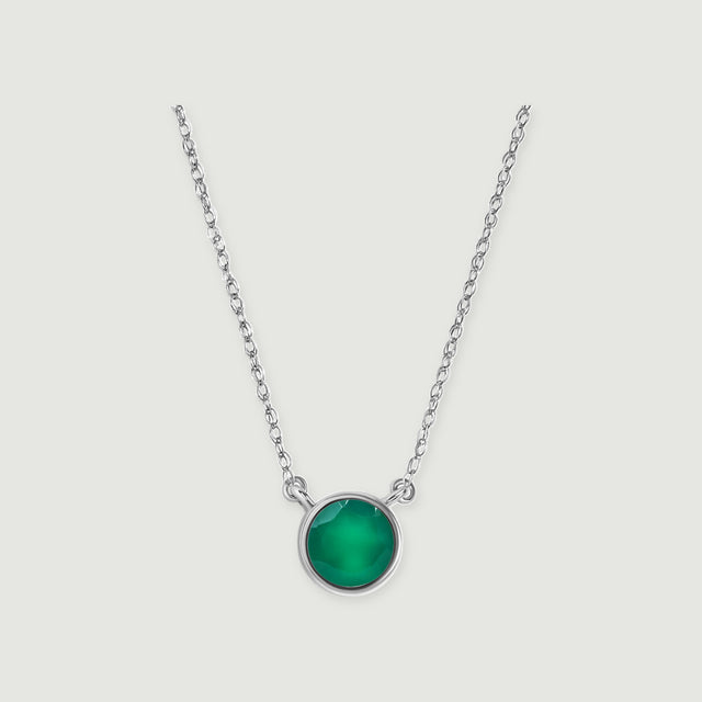 A green onyx stone in a polished white gold setting is attached to a delicate chain on soft gray.