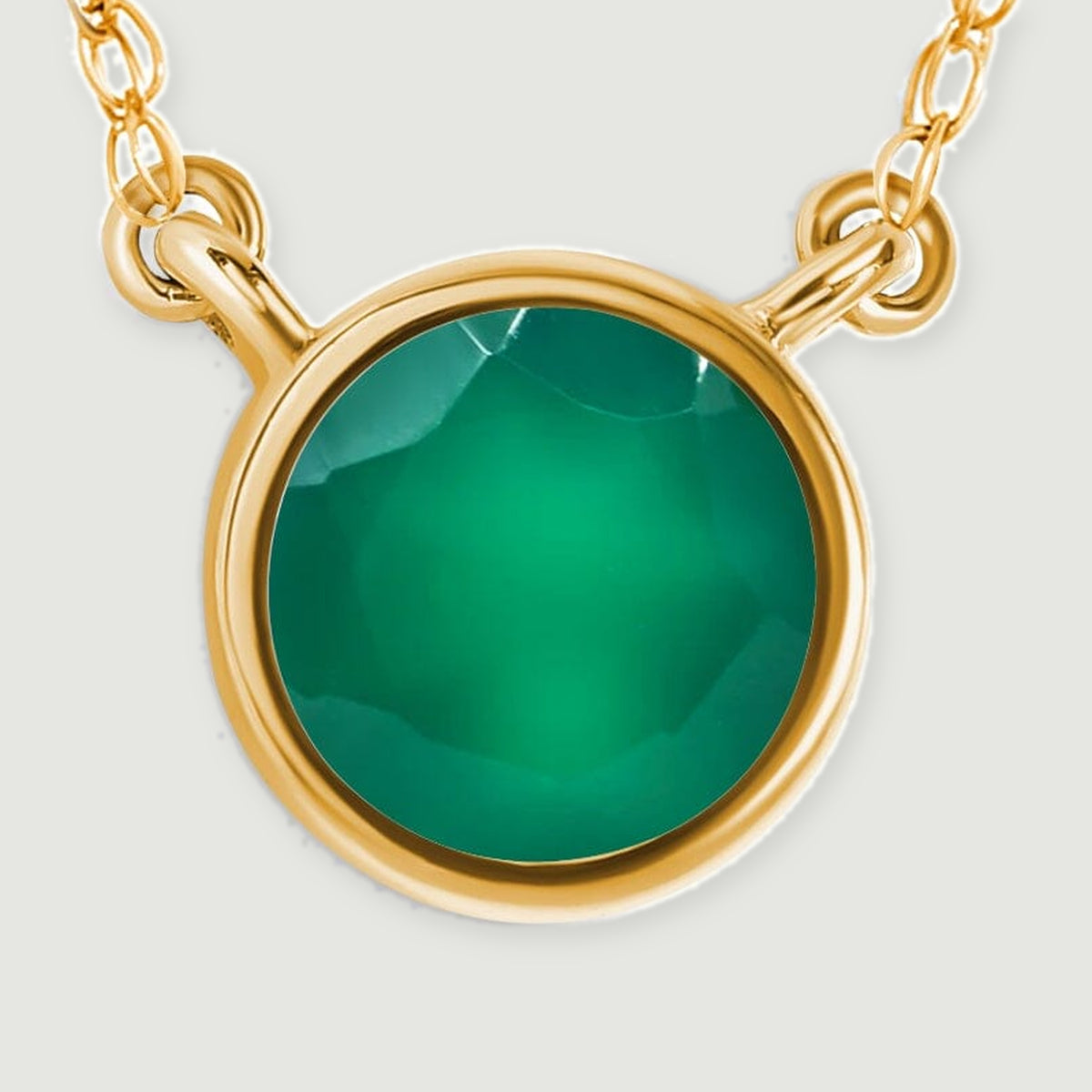 A close view shows the green onyx facets, smooth yellow gold bezel, and two chain attachment loops.