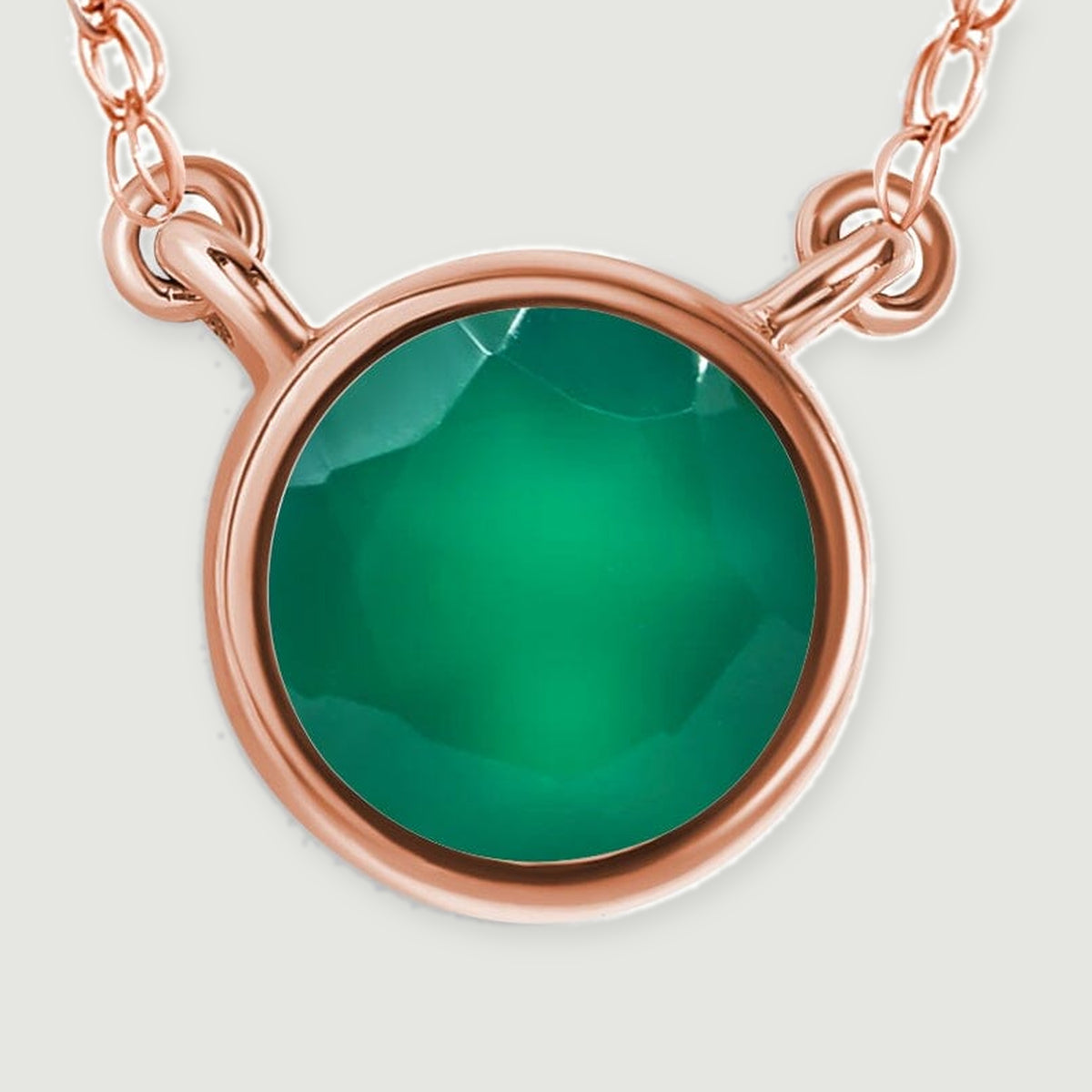 The circular green gemstone and curved rose gold rim fill a close-up with short chain sections above.