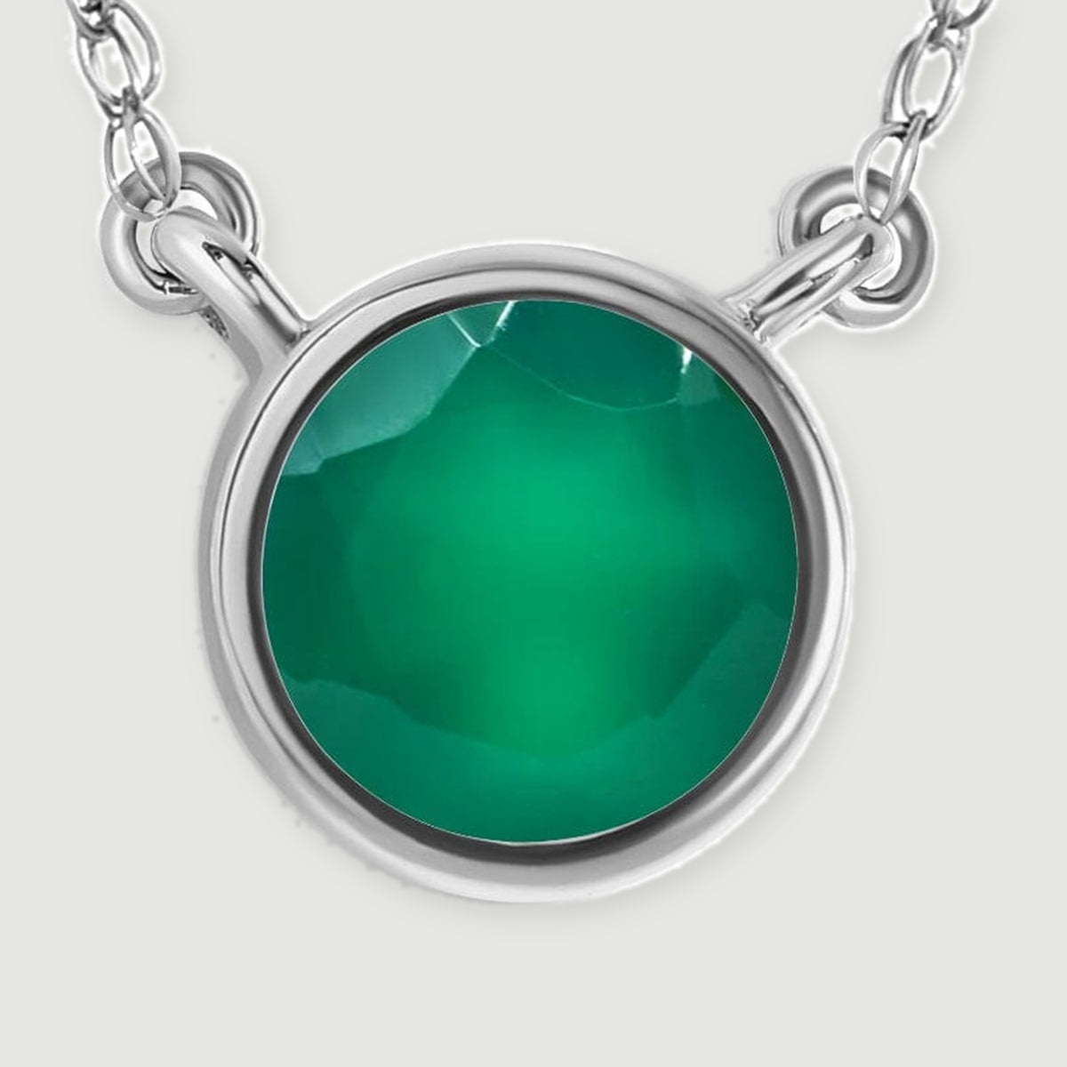 A polished white gold bezel surrounds a faceted green onyx stone in this detailed pendant view.