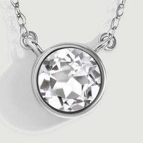A close-up reveals angular white topaz facets inside a white gold rim with two side attachment loops.
