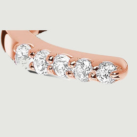 Five clear round diamonds sit in rose gold prongs along the left end of the open ring.