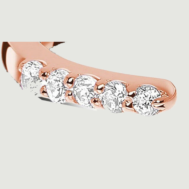Five clear round diamonds sit in rose gold prongs along the left end of the open ring.