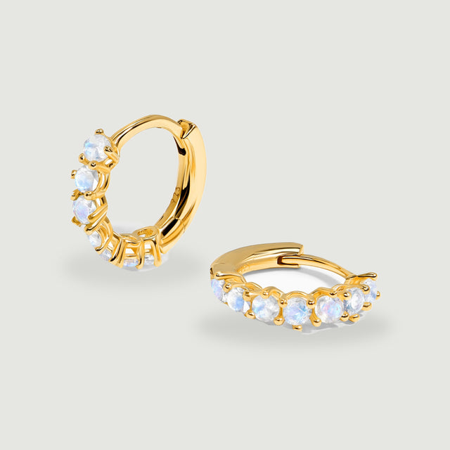 A pair of yellow gold moonstone hoops shows round pale stones and hinged closures.
