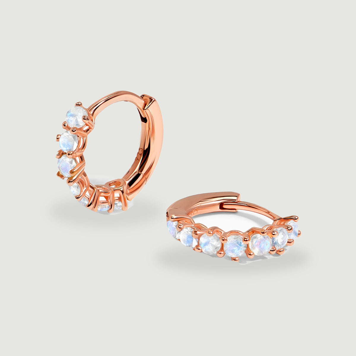 Rose gold moonstone hoop earrings display warm metal tones and blue-white stone reflections.