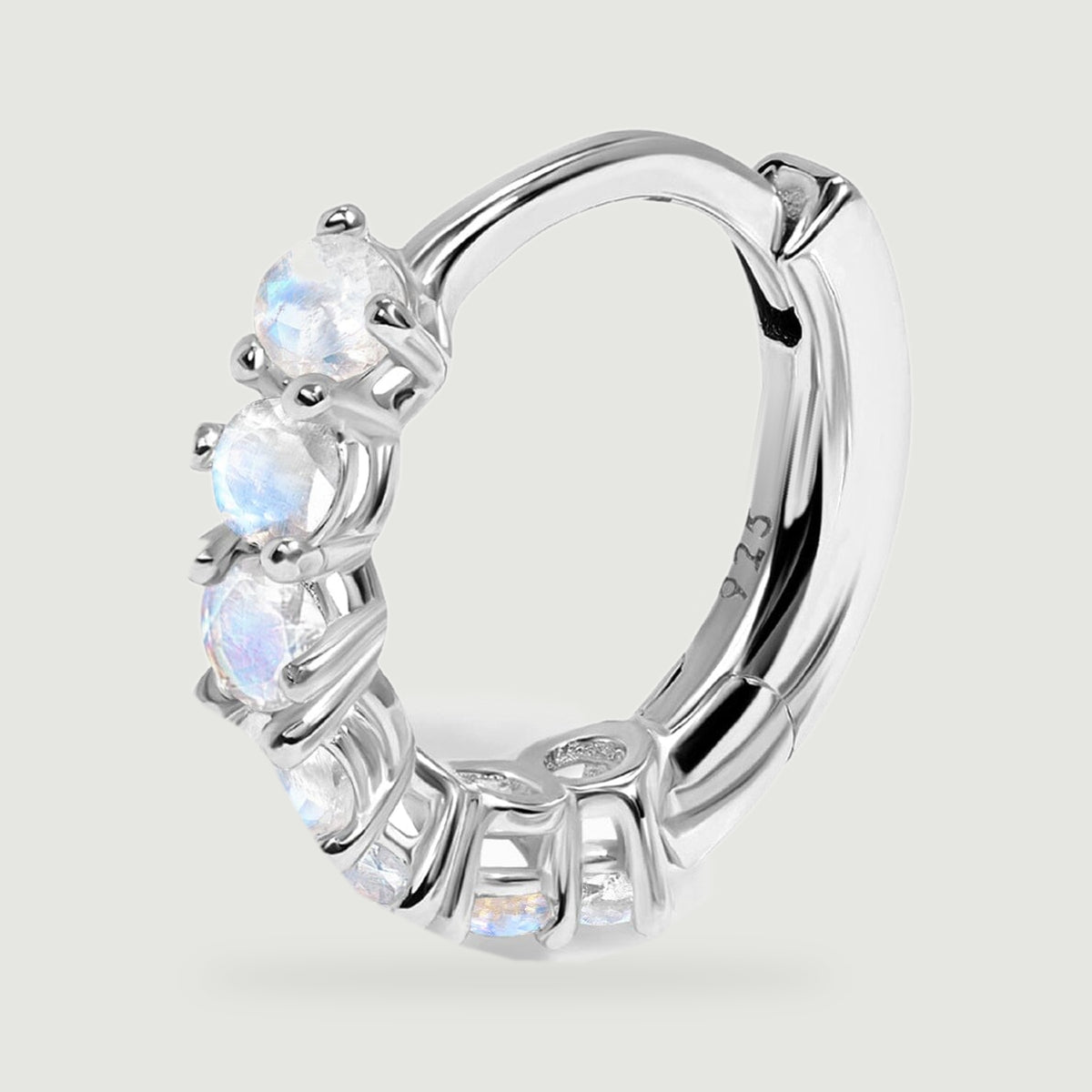 A close view of one silver hoop reveals round moonstones, tiny prongs, and an open circular center.