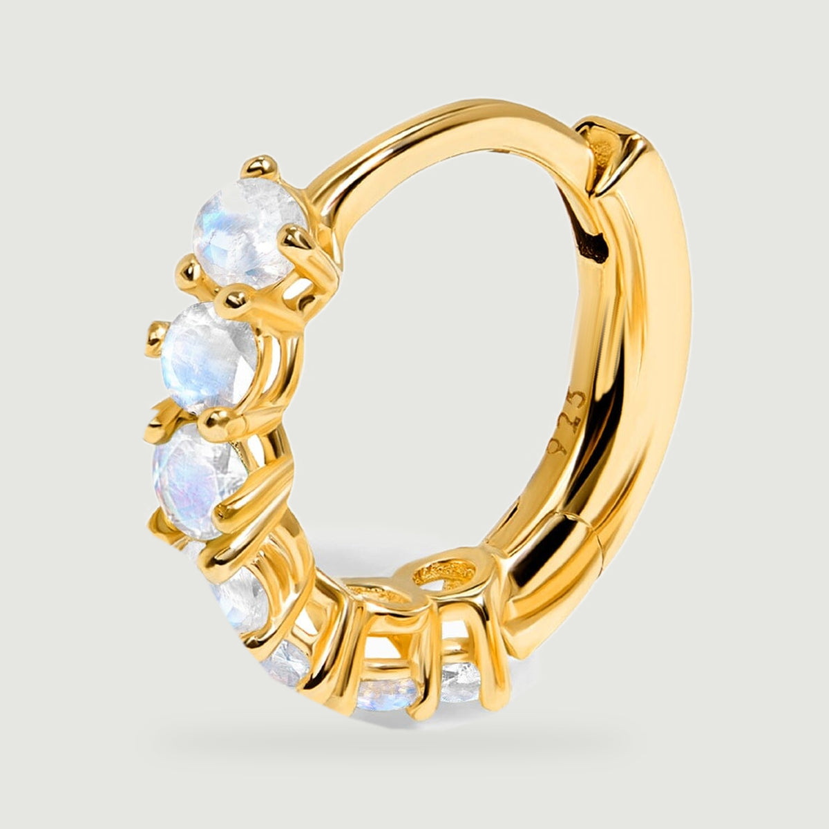 The yellow gold hoop is shown closely with pale faceted moonstones along its curved front.