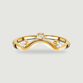 Three clear round stones follow the curved front of a yellow gold ring on light grey.