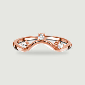 A rose gold wave ring with three bright round stones is centred above a soft shadow.