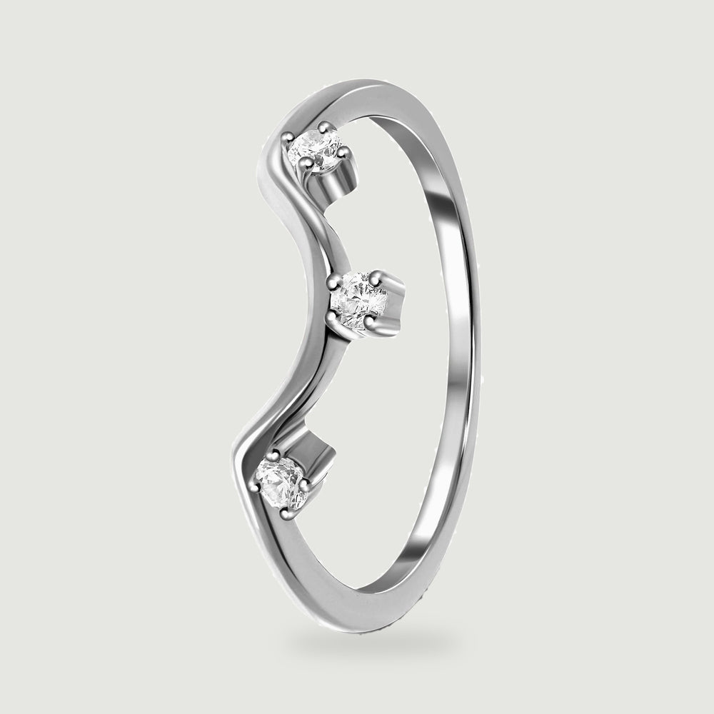 An angled silver ring shows its curved band and the raised prongs around three clear stones.