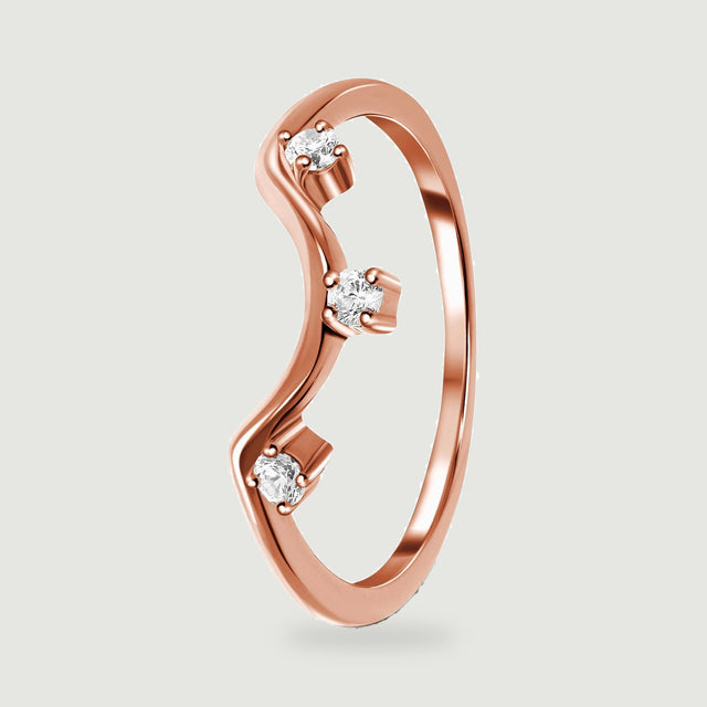 A rose gold ring stands at an angle with its wavy front and three clear stones in view.