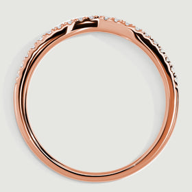 A rose gold ring stands at an angle with open spaces beneath the diamond settings.